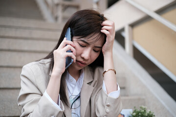 Depressed female office worker talking on mobile phone about her job loss and dismissal