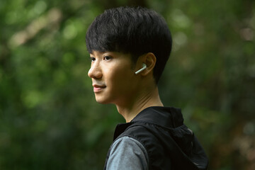 Young sportsman wearing earphones earbuds and looking away. Healthy lifestyle concept