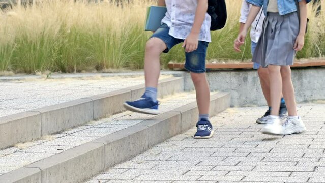Legs of little schoolchildren walking through the school yard. All children are wearing sneakers.