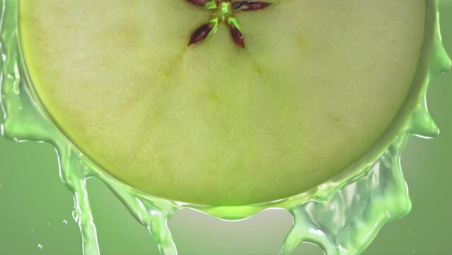 Flowing Green Apple Juice from Apple slice , macro shot in slow motion