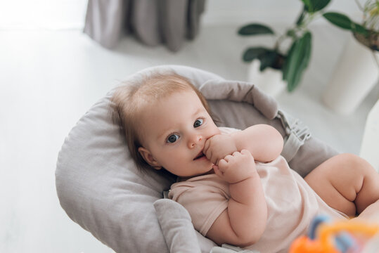 The baby lies in a highchair or highchair in a bright room