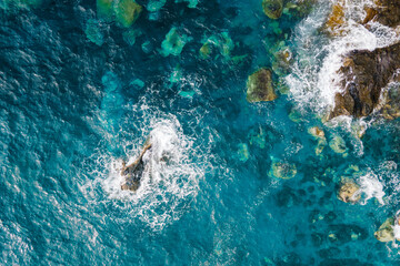 Top down aerial view of shore reefs with ocean waves crashing on rocky coastline