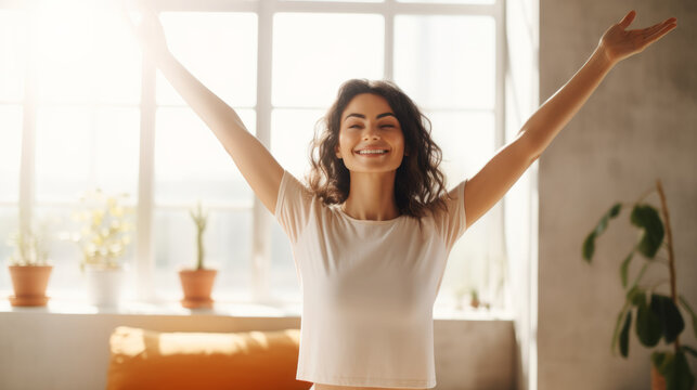Smiling woman stretching her back, straighten her arms up, on a yoga mat, at home, peaceful style