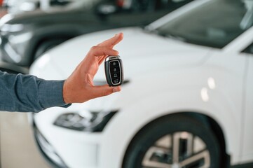 Hand is holding the keys. Close up view of man that is with electrical car