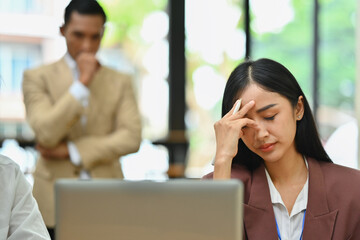 Overwhelmed female employee having problems, feeling tired at corporate meeting. Stress at work concept