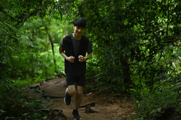 Young male athlete jogging in green forest. Sports, adventure and healthy lifestyle