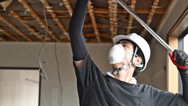 Video of close-up of young masked workers at a construction site, demolishing ceilings, etc.