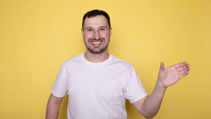 Portrait of excited young man holding something invisible in hand. Positive male showing empty mockup place for ad, banner. 