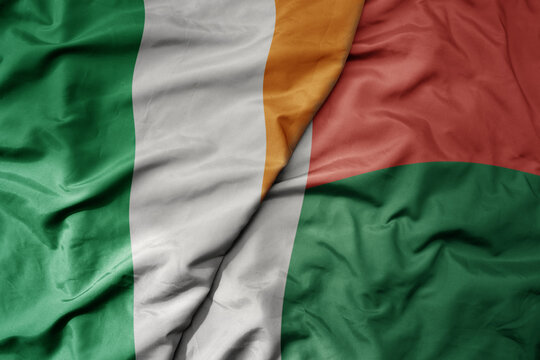 big waving national colorful flag of ireland and national flag of madagascar .