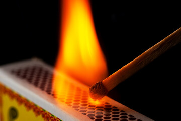 A matchstick lights after it is struck agains the flint surface of a match box. Everything is real,...