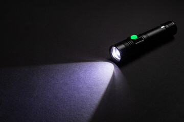 Flashlight and a beam of light in darkness. A modern led lamp with bright projection on dark table.