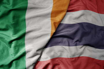 big waving national colorful flag of ireland and national flag of thailand .