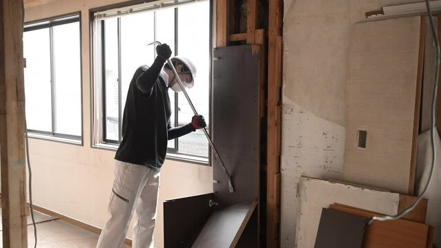 建築現場で働く若いマスクの作業員　内装の解体の動画　バールで壁を壊す