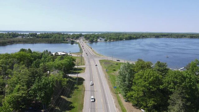 Road leading to small town of Cadillac over lake water, aerial drone view