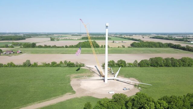 Construction of wind turbine in fields of rural America, aerial orbit view