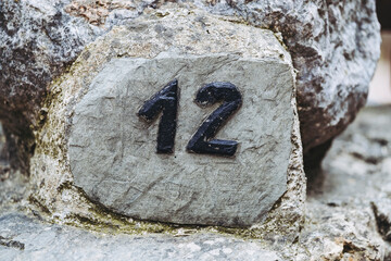 Plaque de rue en ardoise pierre naturelle avec numéro douze - Signe sur le mur d'une maison...