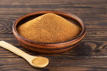 Unrefined cane brown sugar Panela in a clay bowl with wooden spoon on a wooden table.