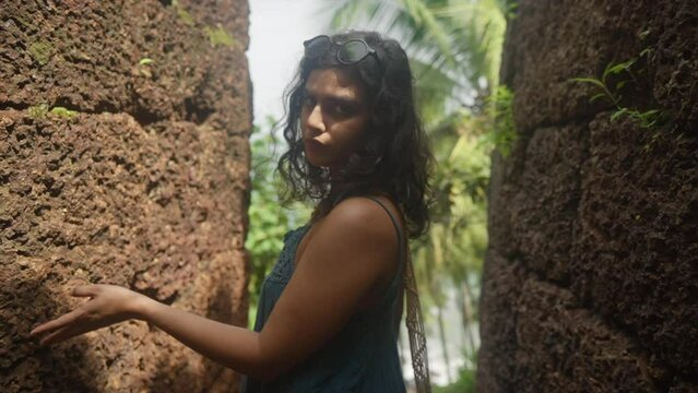 Model standing in a passage of an old fortress of laterite walls and posing for camera