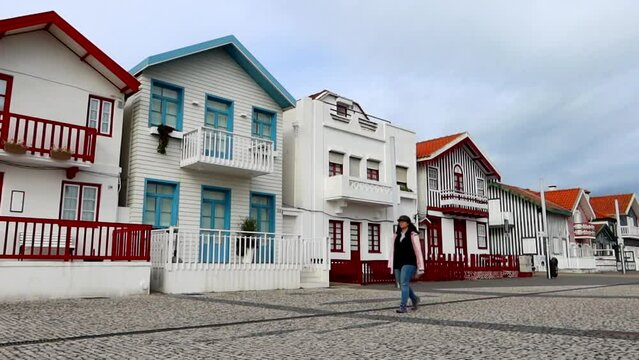 Woman walking alone in Costa Nova with small colorful houses in background