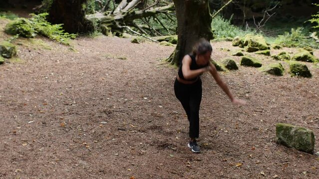 Joyful teenage girl trying out capoeira in forest meadow. frontal