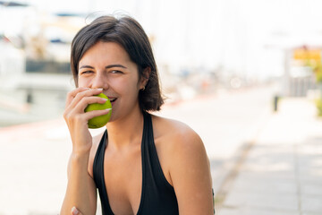 Young pretty Bulgarian woman at outdoors eating an apple