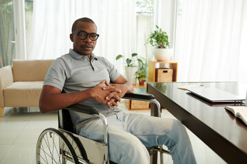 Portrait of Black man with disability sitting in wheelchair at home