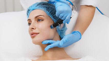 Cosmetologist doing hydrafacial treatment on woman face in beauty clinic