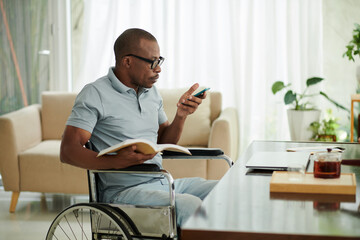 Black man with disability checking notifications in smartphone