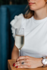 woman holds a glass of cold prosecco in her hand