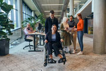 A diverse group of business colleagues is having fun with their wheelchair-using colleague, demonstrating their attention and inclusivity in the workplace
