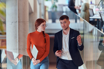 Fototapeta premium In the dynamic environment of a modern startup company, the director engages in a discussion with his young business colleague while they walk, reflecting the spirit of collaboration and innovation in