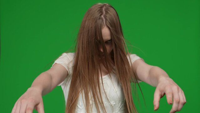 Medium green screen, chroma key video of a posessed female, woman figure, ghost, poltergeist, zombie pulling her hands out to the camera, growling, grinning. Hair is covering her face. Chroma key.