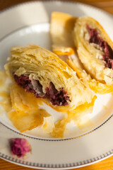 Homemade cherry strudel cut into slices on white porcelain plates on lace tablecloth