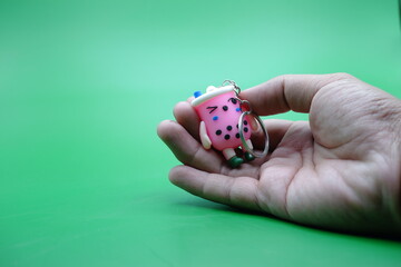 hand holding a cute key chain on a green background