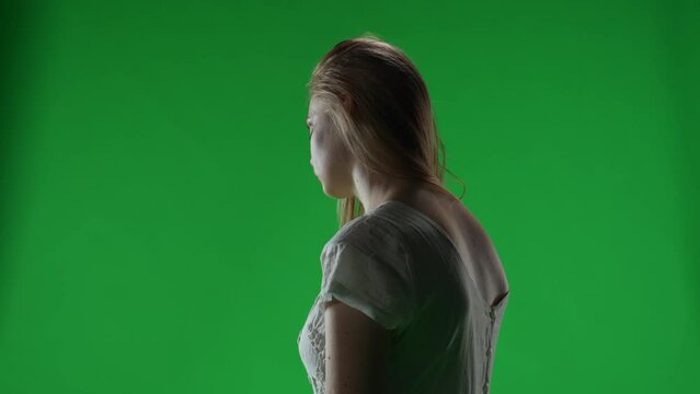 Medium green screen, chroma key video of a posessed female, woman figure, ghost, poltergeist, zombie turning her face to the camera with a dead look. Hair is covering her face. Chroma key.