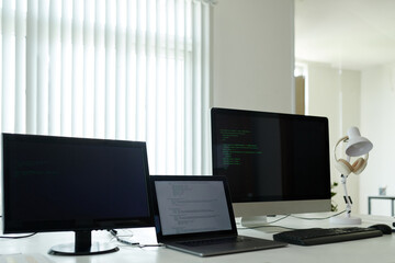 Laptop and computers with programming code on table in office