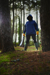 Terrifying Halloween Scene: Hooded Figure in Gardener's Gloves and Rubber Boots Wielding Machete,...