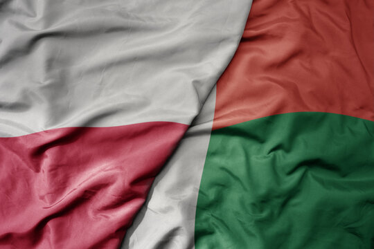big waving national colorful flag of poland and national flag of madagascar .