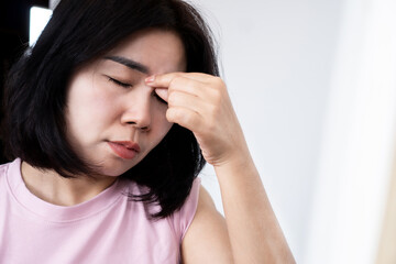 asian woman suffering from pain between eyebrows and eyes caused by headache, sinus infection