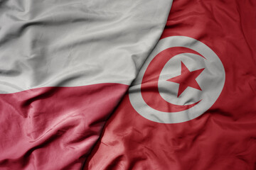 big waving national colorful flag of poland and national flag of tunisia .