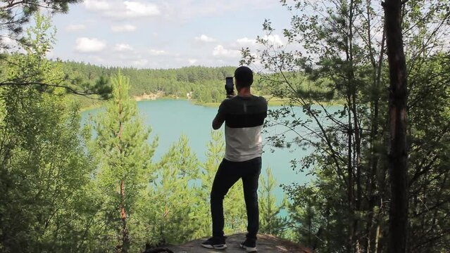 a man makes content on a forest lake