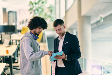 Obraz premium In a modern office setting, an African American businessman engages in a discussion with his director, using a tablet to address business challenges, symbolizing collaboration and technology