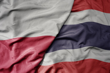 big waving national colorful flag of poland and national flag of thailand .