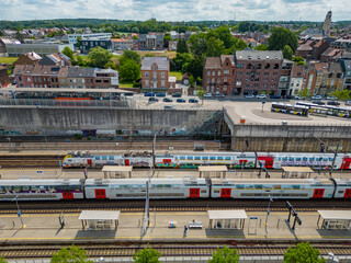 Halle, Flemish Brabant Region, Belgium, 01 05 2023, aerialview of the railway station in the city of Halle on a sunny spring day, showing the Belgian trains on the tracks at the platforms. High
