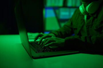 Hacker working on laptop in neon green office room