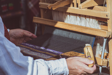 A craftswoman working on an ancient wooden weaving loom in a arts and crafts fair in Vilnius, Lithuania 