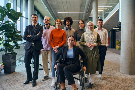 In a spacious and modern startup office, a diverse group of business colleagues, including a colleague in a wheelchair, collaborates and interacts, exemplifying inclusivity, diversity, and teamwork in