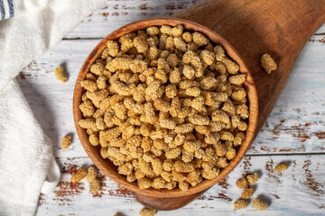 Dried mulberries in wooden bowl. Sun-dried mulberry on a white wood background. Top view
