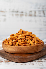 Peanuts with sauce in wooden bowl. Peanuts with sauce on a white wood background