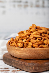 Peanuts with sauce in wooden bowl. Peanuts with sauce on a white wood background. Close up